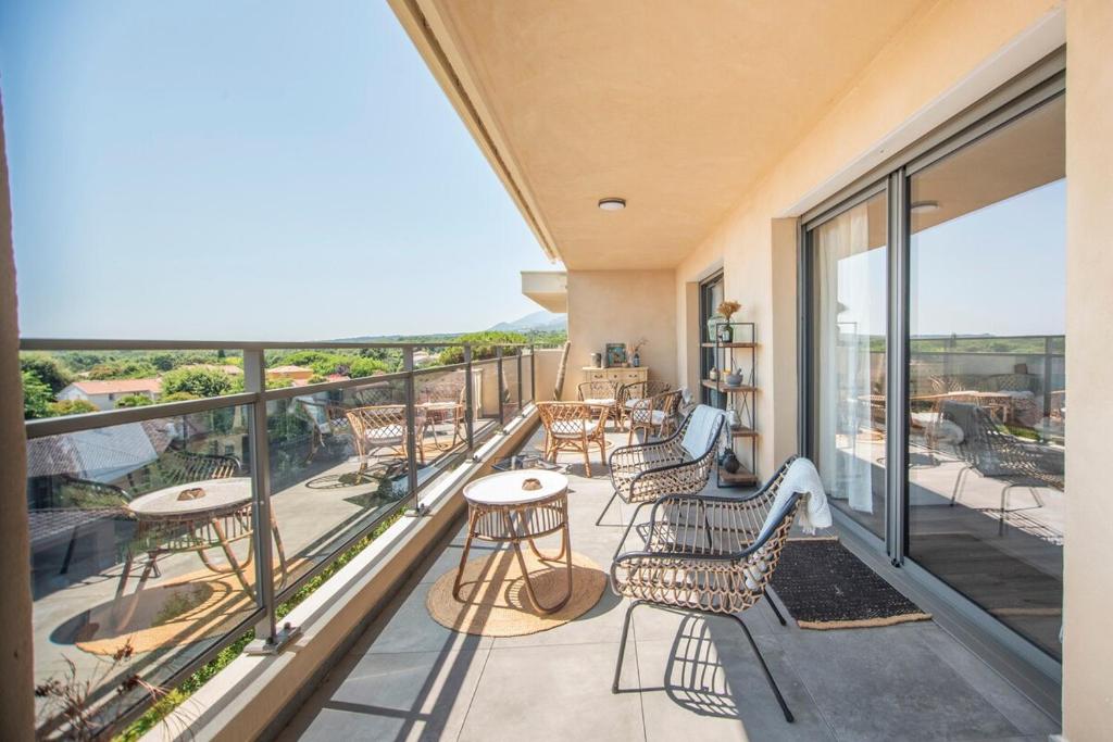 a balcony with tables and chairs and windows at 2 bedroom Sun & Terrace with sea view in San-Nicolao