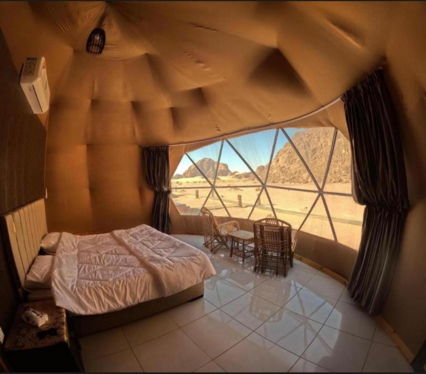 a bedroom with a bed and a large window at Wadi Rum Abu Khaled in Wadi Rum