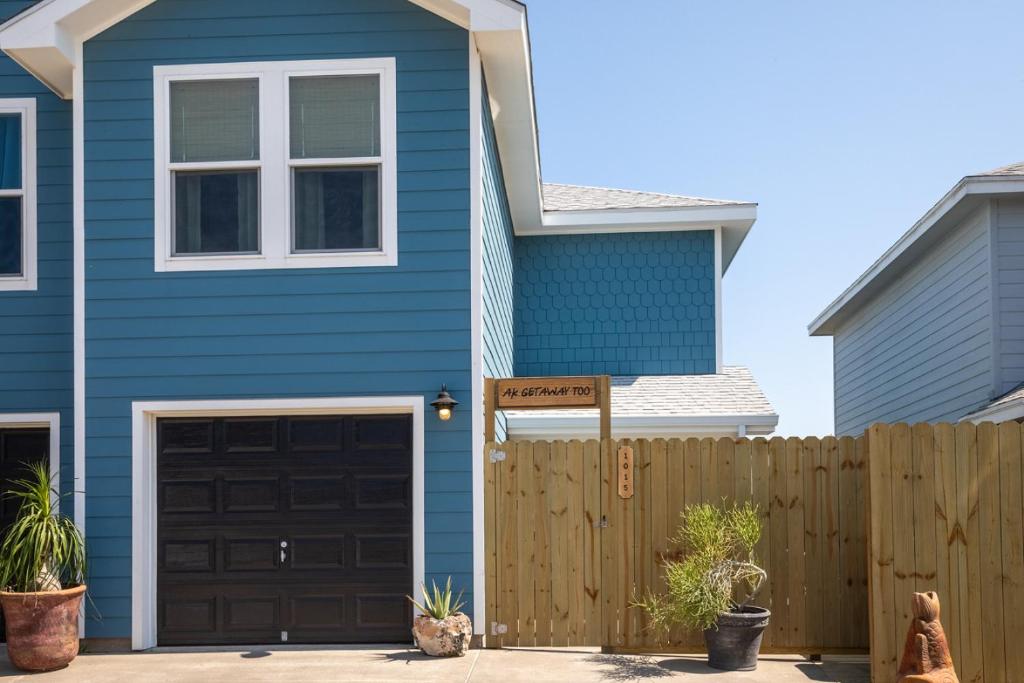 a blue house with a wooden fence in front of it at AK Getaway Too ,where the waves the shore and worries melt away. in Port Aransas