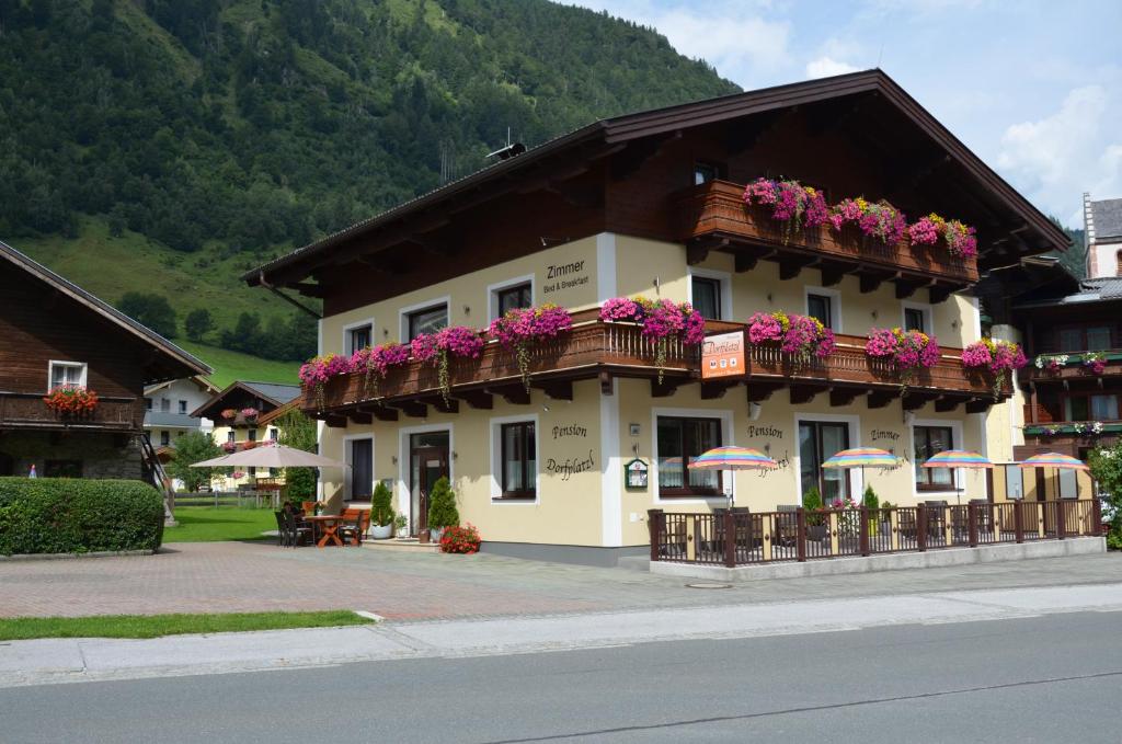 un edificio con un balcón con flores. en Pension Dorfplatzl, en Fusch an der Glocknerstrasse