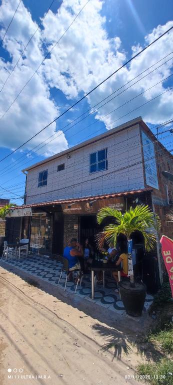 a building with people sitting at a table outside at Kitnet in Itaparica Town