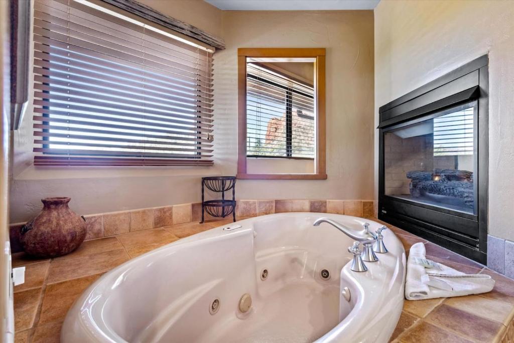 a large white tub in a bathroom with windows at Adobe Village Studio Suite- Sundance in Oak Creek