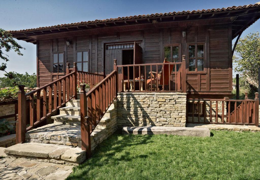 een blokhut met een trap naar een veranda bij Радева къща Жеравна in Zheravna