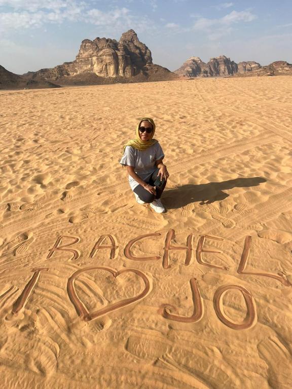 una persona sentada en el desierto escribiendo en la arena en Wadi Rum Sand moon Camp &Tour, en Wadi Rum