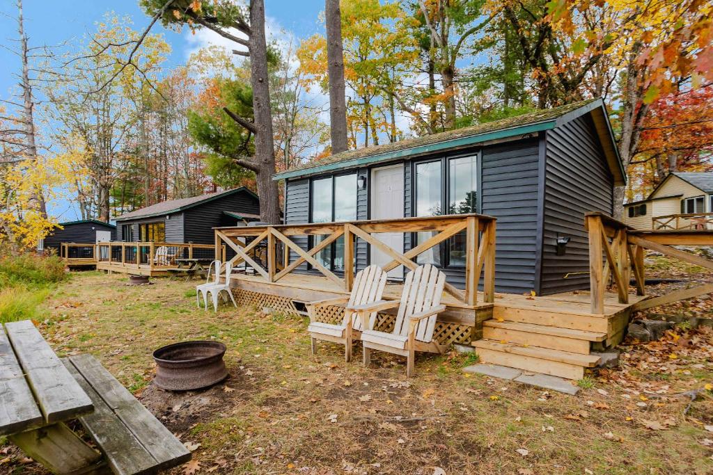 a black tiny house with two chairs and a porch at Studio Cottage #9 - Virginia Pine in Gravenhurst