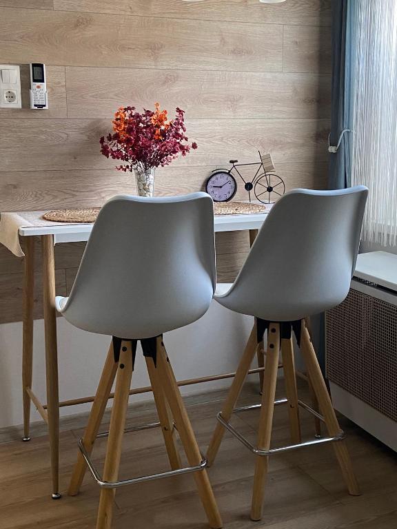 two chairs at a desk with a vase of flowers at Szeged Sunshine Apartman in Szeged