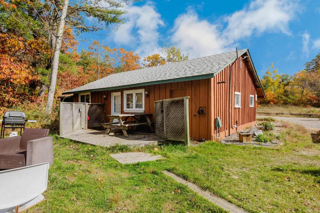 eine rote Scheune mit einem Picknicktisch im Hof in der Unterkunft Pine Lake 3-Bedroom Cottage #12 - The Gallery in Gravenhurst