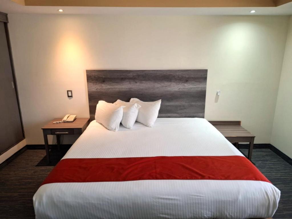een hotelkamer met een groot bed en een telefoon bij Hotel ALO! Express in Torreón