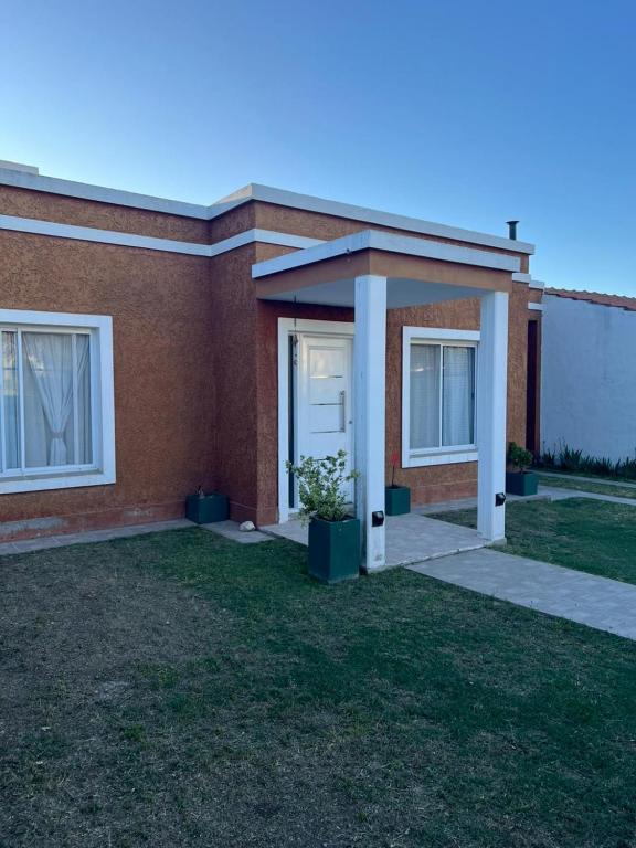 ein Backsteinhaus mit einer weißen Tür und einem Rasenplatz in der Unterkunft Luna Vallista House in Mina Clavero