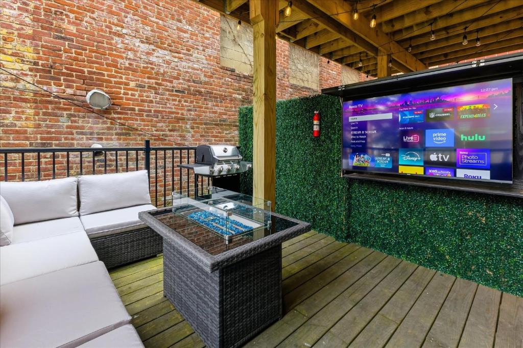 eine Terrasse mit einer Couch und einem Großbildfernseher in der Unterkunft Mass Ave Retreat with Big Patio and Free Parking in Indianapolis