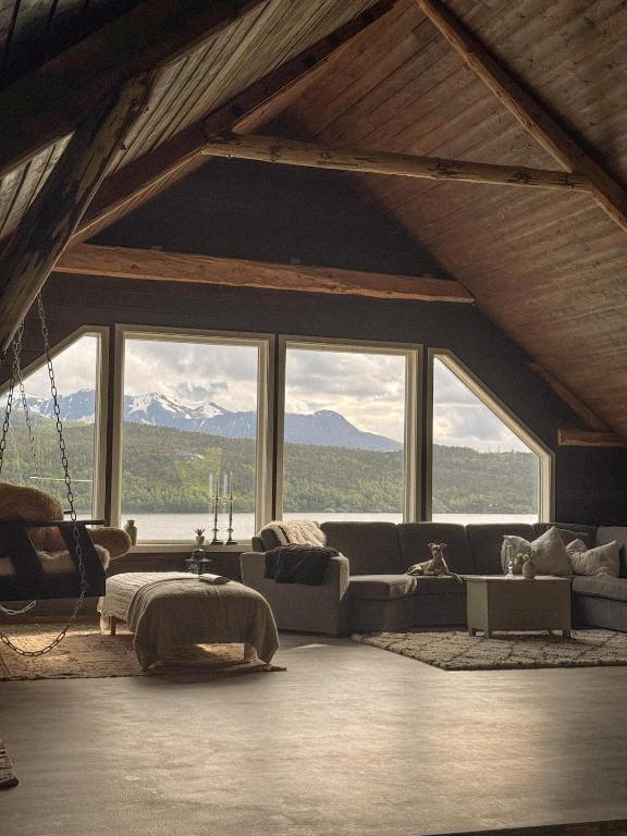 a living room with couches and windows with mountains at Åsjord Farmhouse in Oldra
