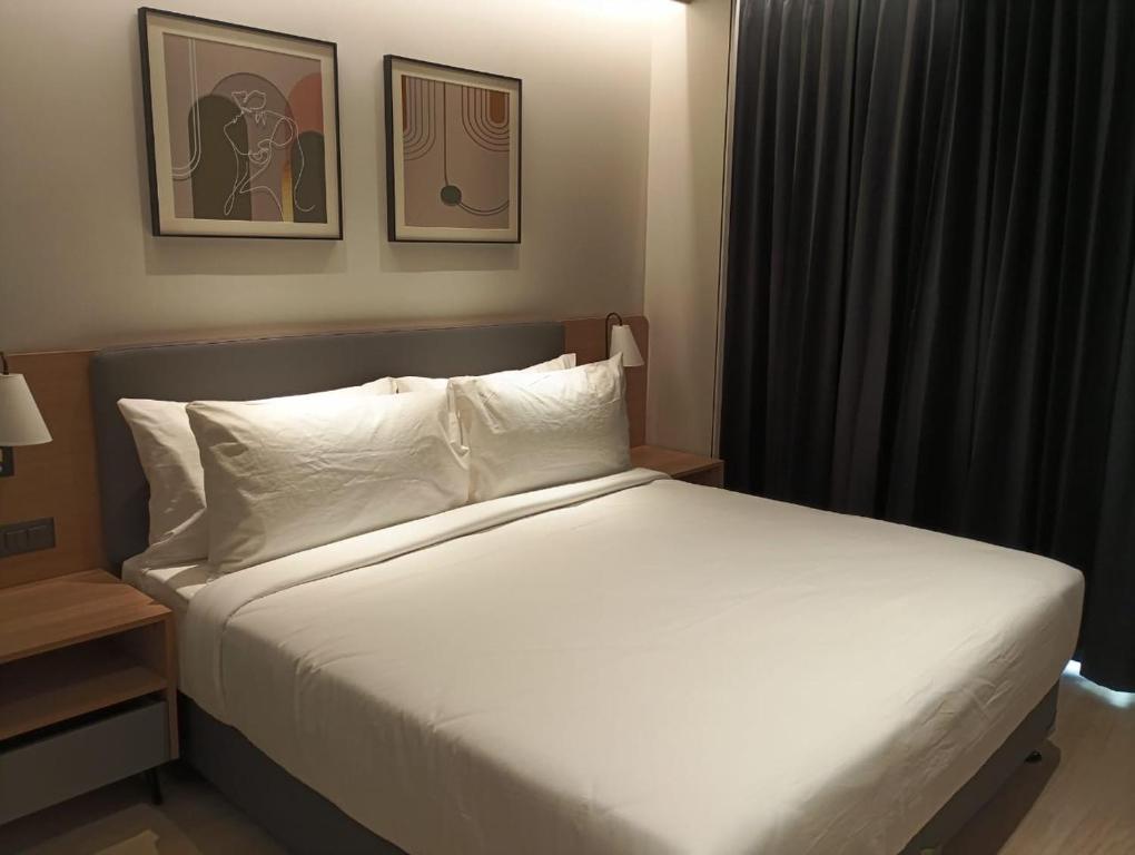 ein Schlafzimmer mit einem großen Bett mit weißen Laken und Kissen in der Unterkunft Luxury Studio, 1 Bed, Separate Study Gourmet Kitchen Prime Location in Bangalore