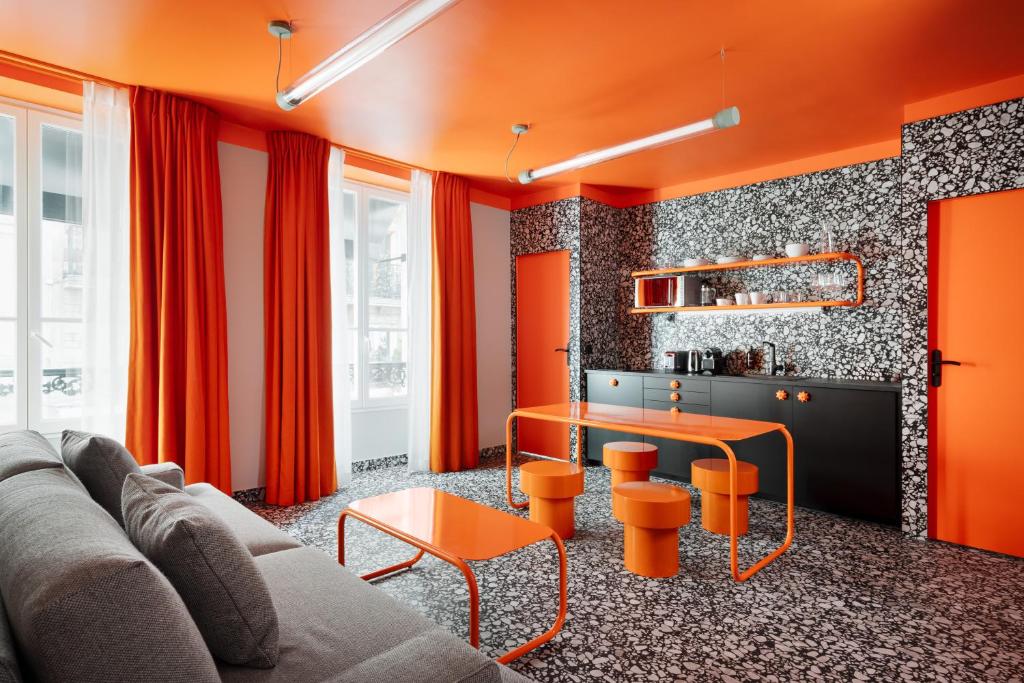 un salon avec des murs orange et une table dans l'établissement Beauquartier - Chemin Vert, à Paris