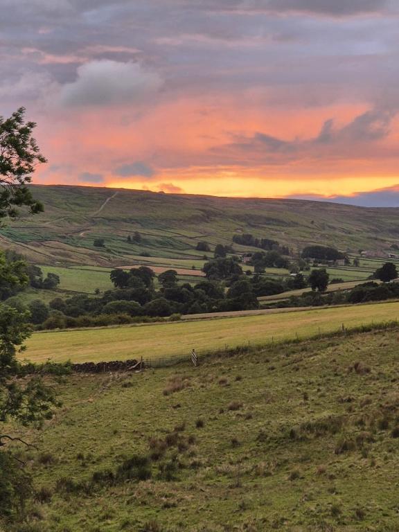 a view of a field with a sunset in the background at Craven Garth Cottages in Rosedale Abbey