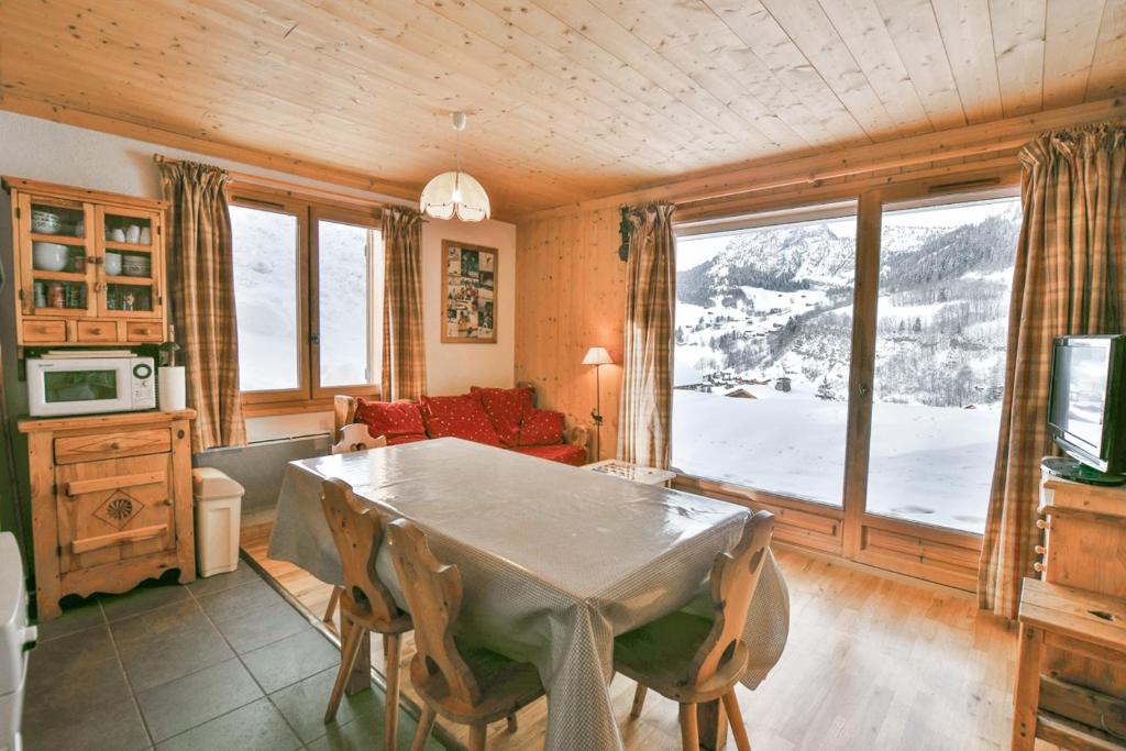 un salon avec une table et une grande fenêtre dans l'établissement Refuge Le Bardeau B1, au Grand-Bornand