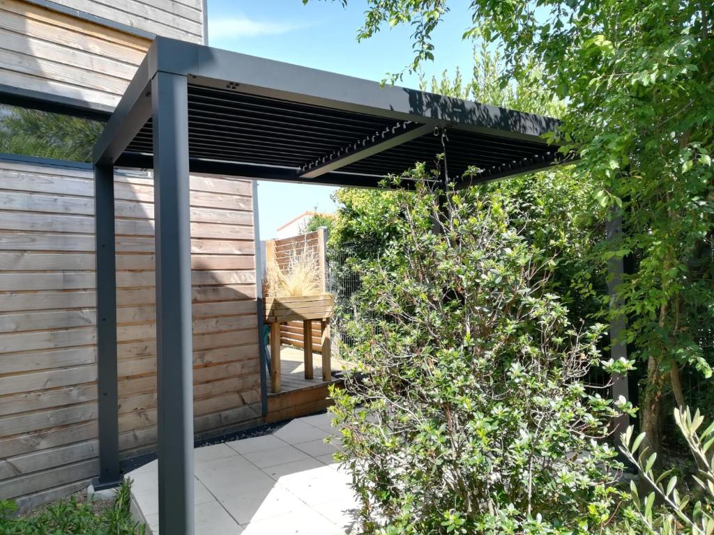 une pergola avec une chaise sur une terrasse dans l'établissement Les Amarres, maison bois avec terrasse proche mer, à La Rochelle