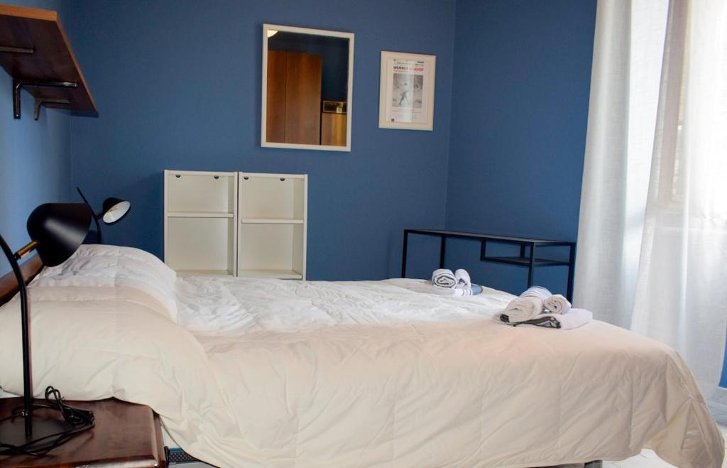 Un dormitorio con una cama blanca con una pared azul. en Monginevro 15 min from the center, en Turín