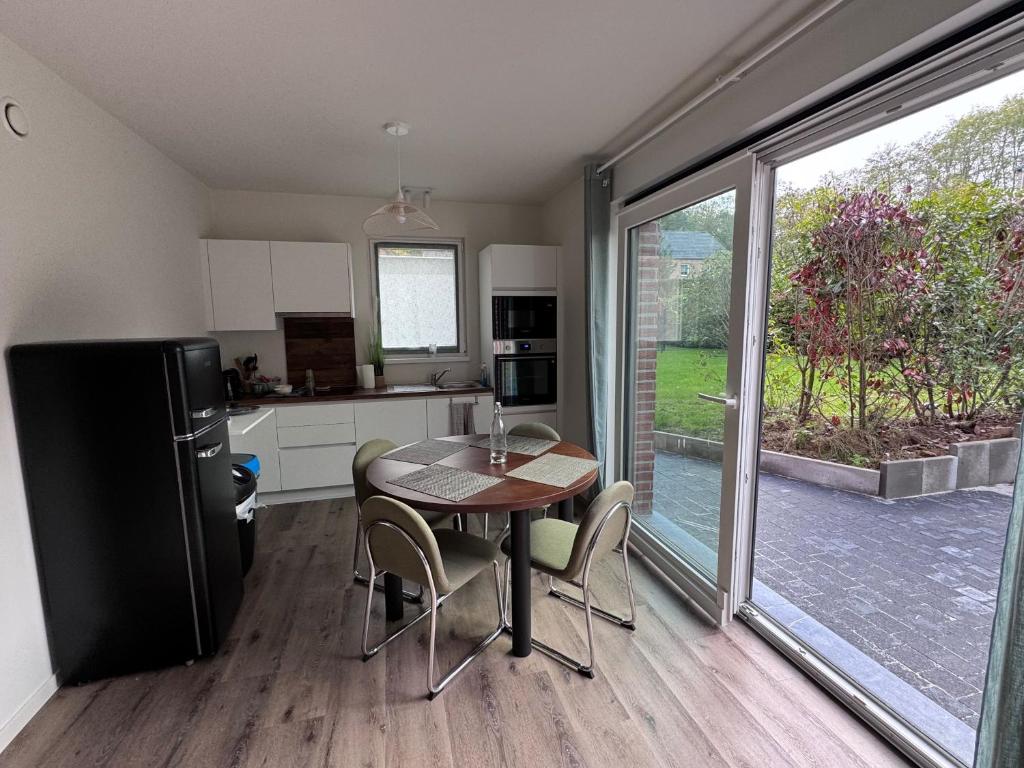 a kitchen and dining room with a table and a refrigerator at Appart Wavre, 2ch, terrasse, piscine, charme & confort in Wavre