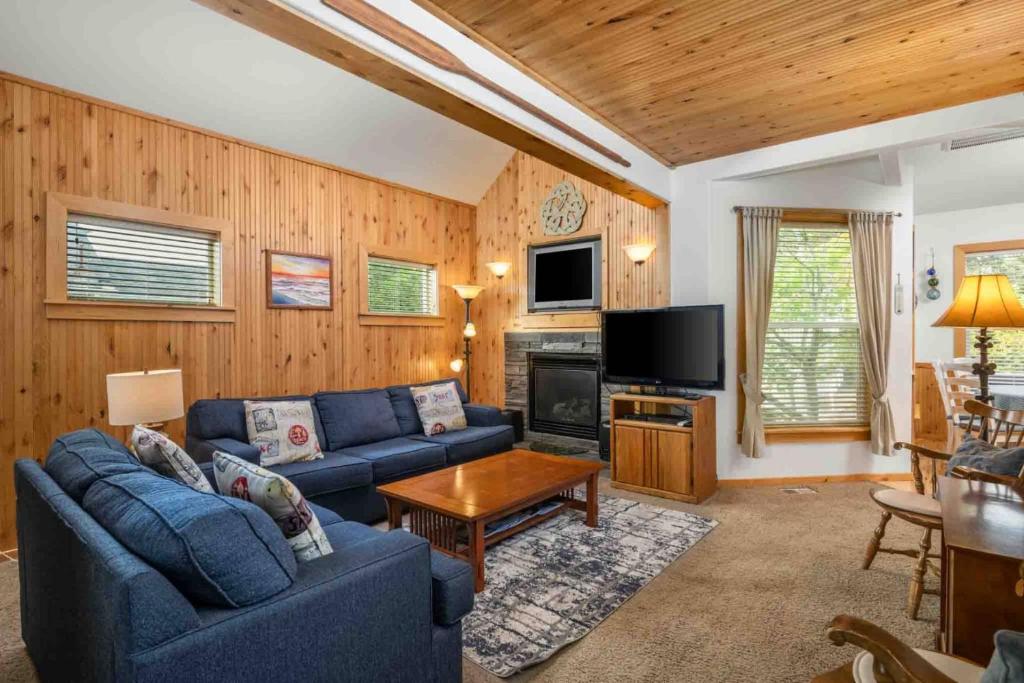 a living room with a blue couch and a tv at Twin Rocks Hideaway in Rockaway Beach
