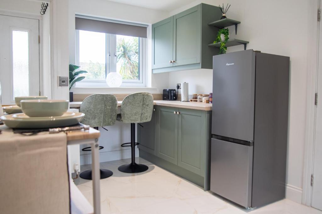 a kitchen with green cabinets and a refrigerator at Sizewell C - Contractor Accommodation in Leiston