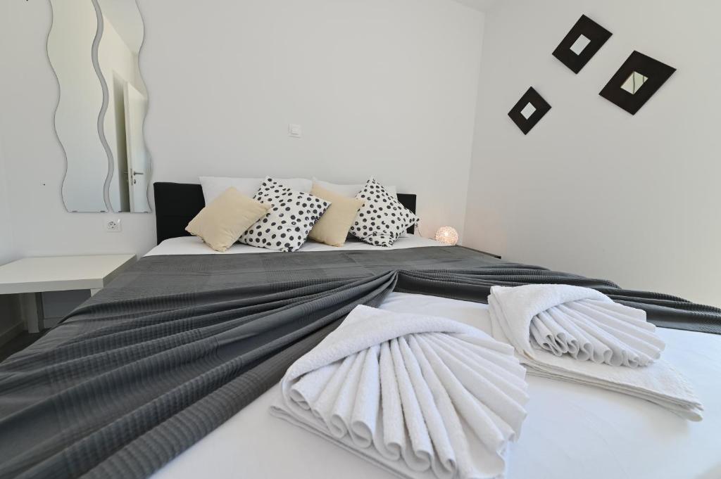 a bed with black and white pillows on it at Azuro Novalja Zrce in Novalja