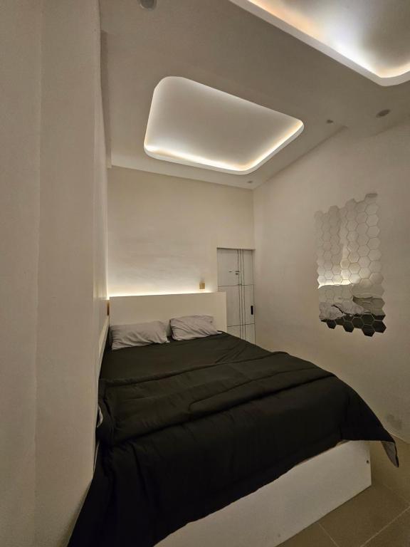 a bedroom with a black bed in a white room at Villa paradise 360 pantai prigi in Tasikmadu