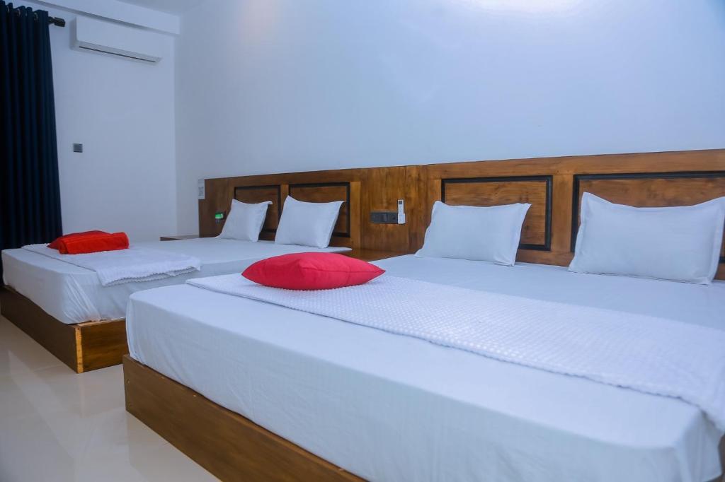 ミリッサにあるOcean Light Mirissaの赤い枕付きのベッド2台が備わる客室です。