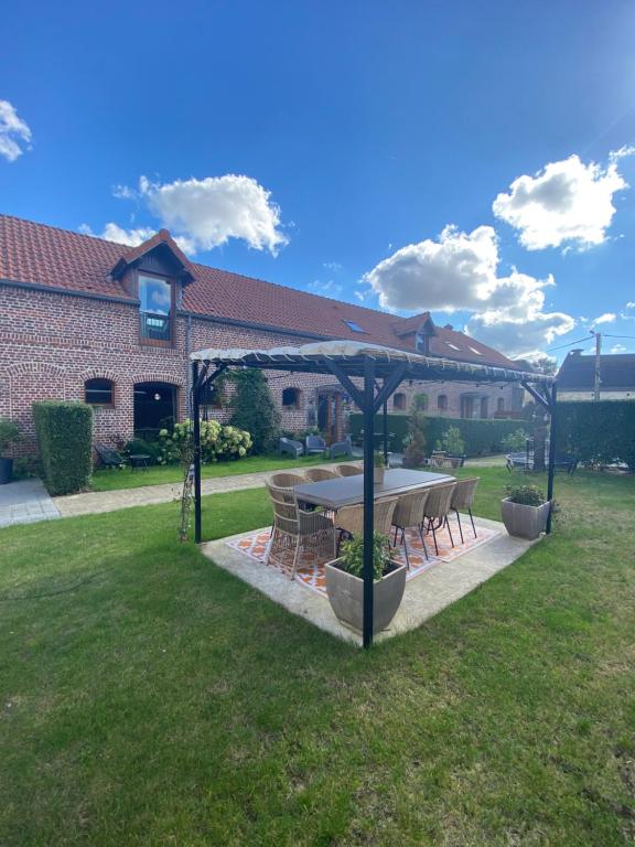 a table and chairs under an umbrella in a yard at Ferme de Montecouvez in Crèvecoeur-sur-lʼEscaut