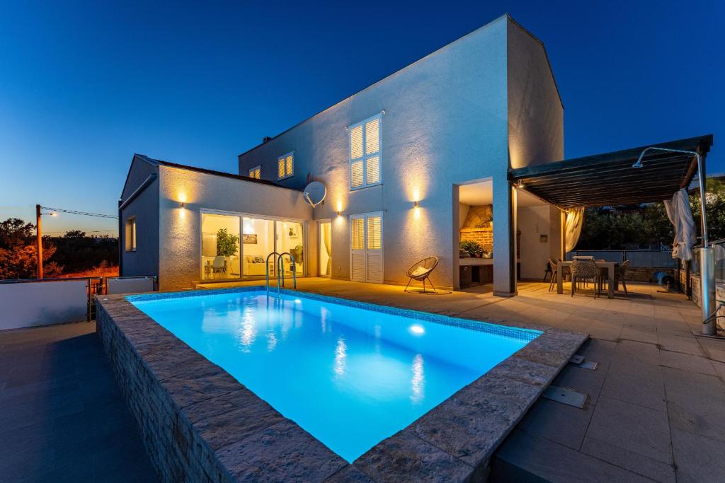 a swimming pool in front of a house at night at MY DALMATIA - Sea view villa Anpero with private heated pool and sauna in Maslenica