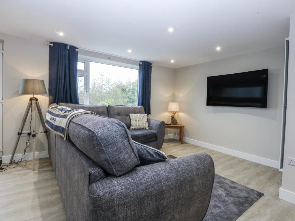 a living room with a couch and a flat screen tv at Caledfryn in Benllech