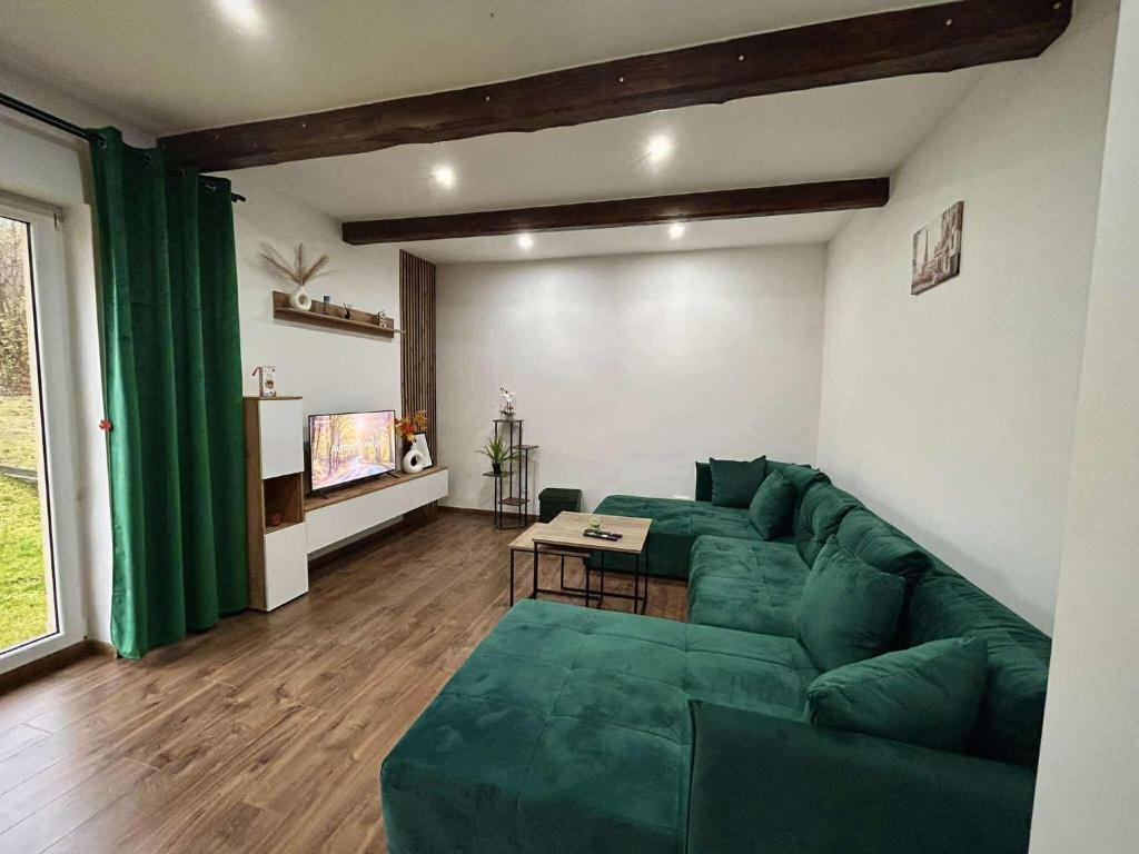 Una sala de estar con un sofá verde y una mesa. en Relax house Tvarožec, 
