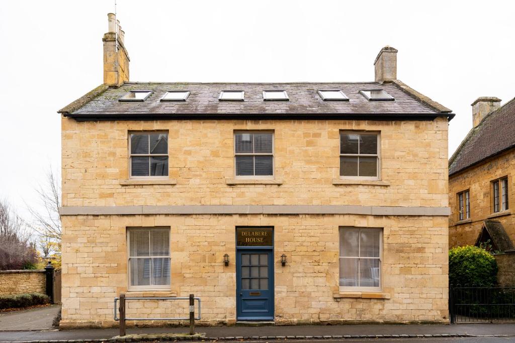 an old brick building with a blue door at Delabere House - Luxury Cotswolds Holiday Apartments in Moreton in Marsh