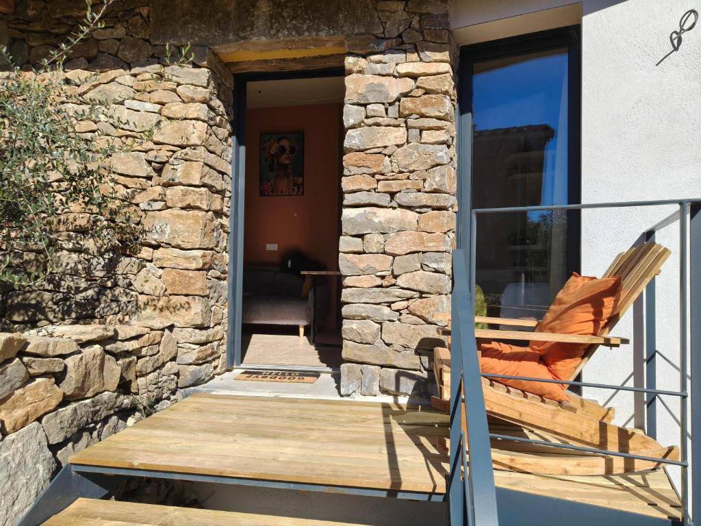 mecedora en un porche con pared de piedra en La Grange d'Andrea, en Saint-Étienne-de-Fontbellon