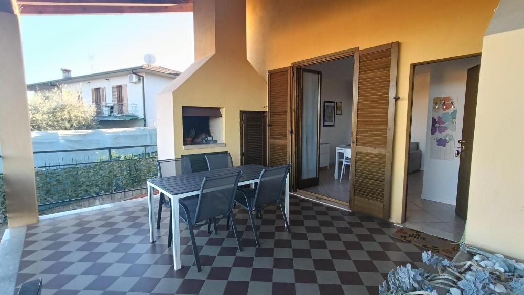 een patio met een tafel en stoelen op een geruite vloer bij Appartamento Polpenazze - Relax in collina con piscina in Polpenazze del Garda