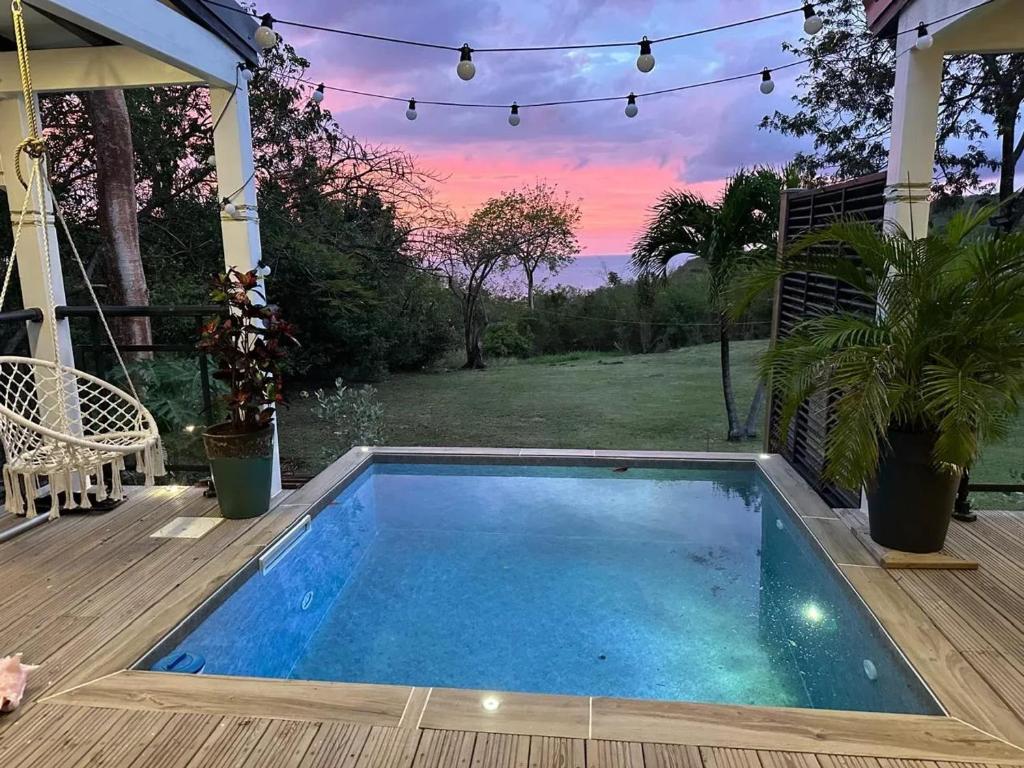 a small swimming pool on a deck with a sunset at Bungalow romantique à Deshaies + piscine in Deshaies