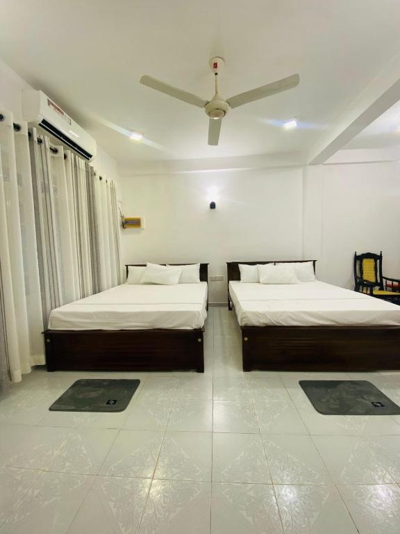 a bedroom with two beds and a ceiling fan at Seavora Tangalle in Tangalle