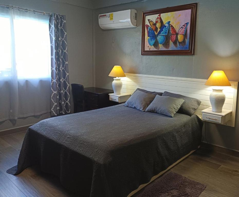 a bedroom with a bed with two lamps and a window at Blue Morpho Suite in Orange Walk