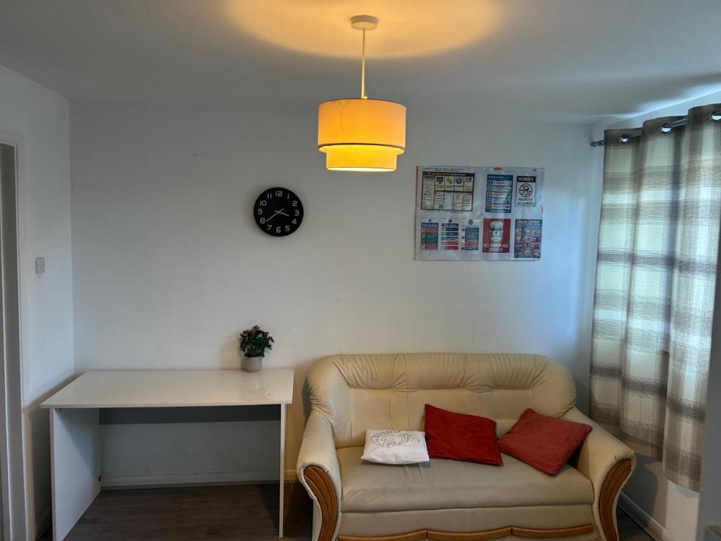 sala de estar con sofá, mesa y reloj en The Sawyers Court Home, en Chatham