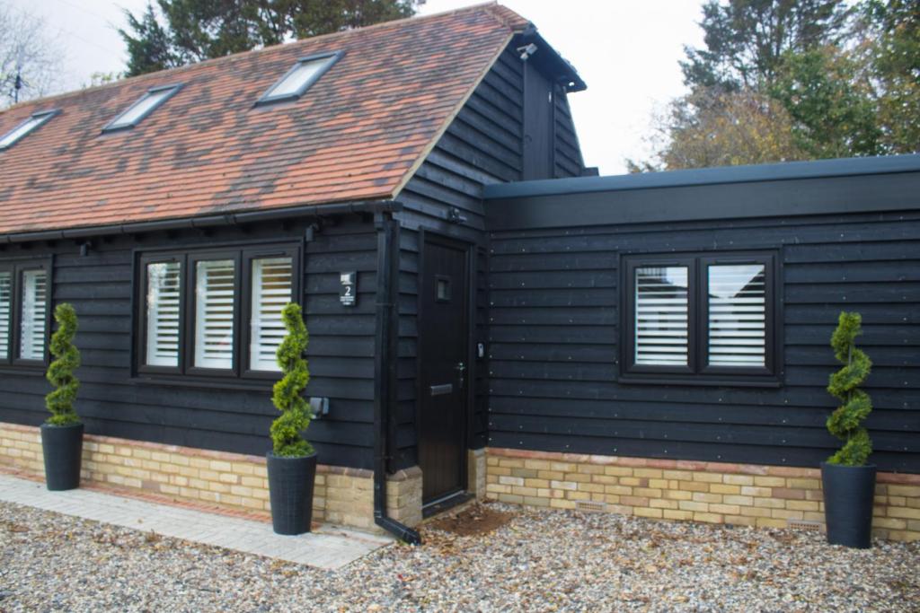 ein schwarzes Haus mit braunem Dach in der Unterkunft Little Dunton Lodges 2 in Brentwood
