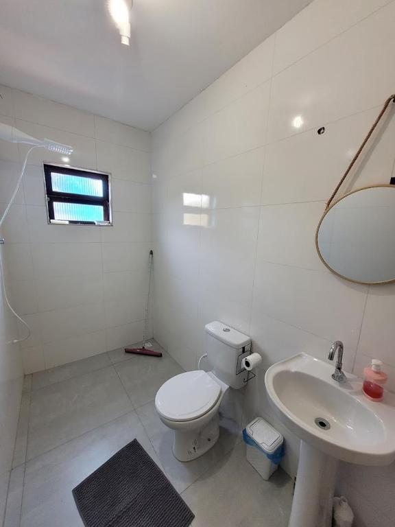 een witte badkamer met een toilet en een wastafel bij Chalé do João in Ubatuba