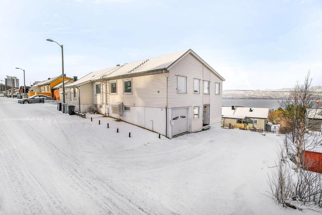 een huis aan een met sneeuw bedekte straat met een oprit bij Aurora Seaview Escape E33 in Slåttvikstrand