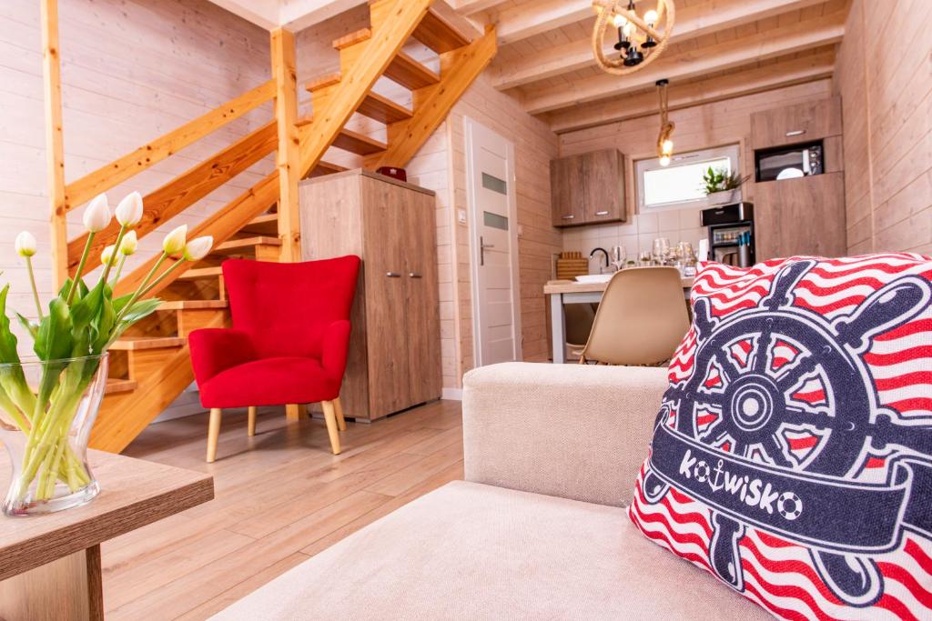 a small living room with a red chair and a kitchen at Kotwisko in Sarbinowo