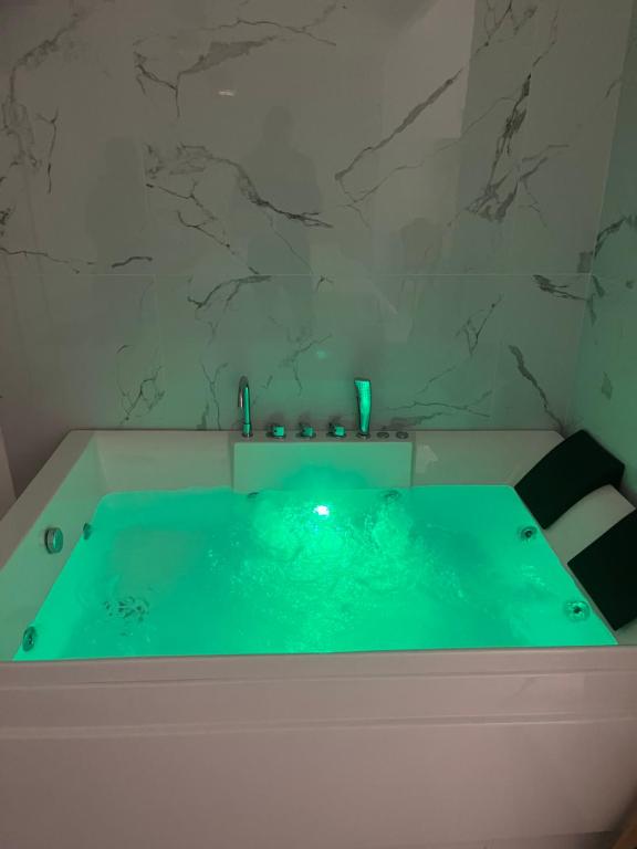 a green tub in a bathroom with a marble wall at Nuvola Luxury suite in Turin