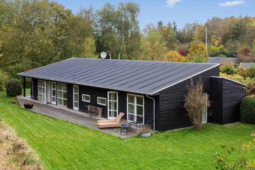 een zwarte hut met een terras in een tuin bij 823-Tisvildeleje-Vibevaenget-13-A in Tisvilde