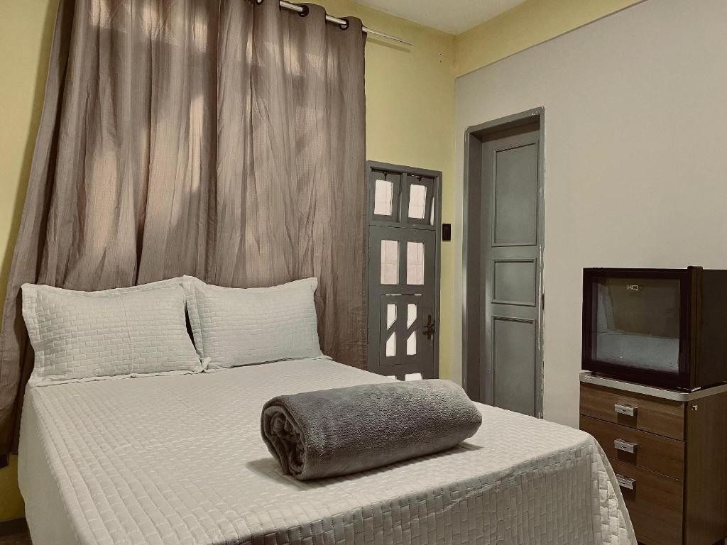 een bed met een kussen erop en een televisie bij CeoHost Studios Premium in Aracaju