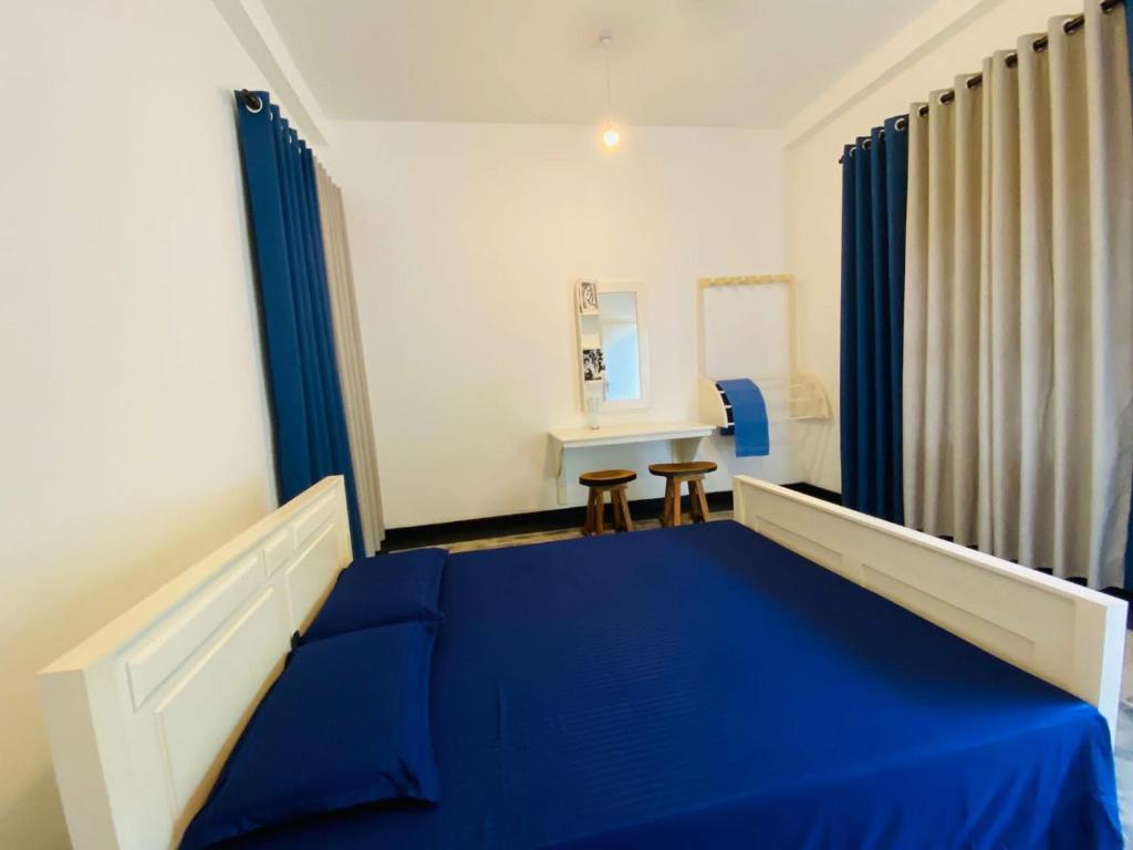 a bedroom with a blue bed and a mirror at Jasmine Chill Cafe & Guest House in Chilaw