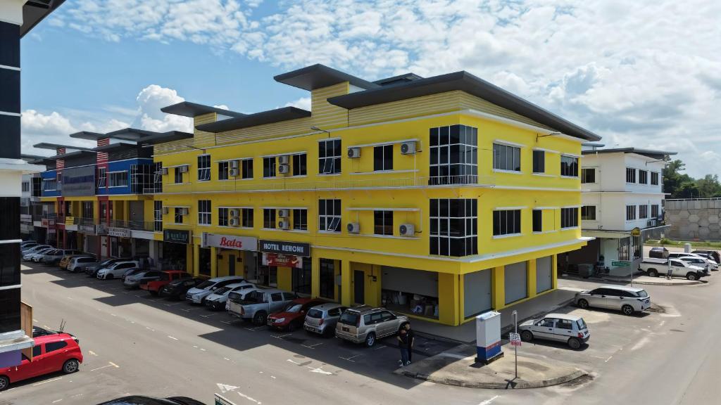 a yellow building with cars parked in a parking lot at Hotel Benoni in Papar