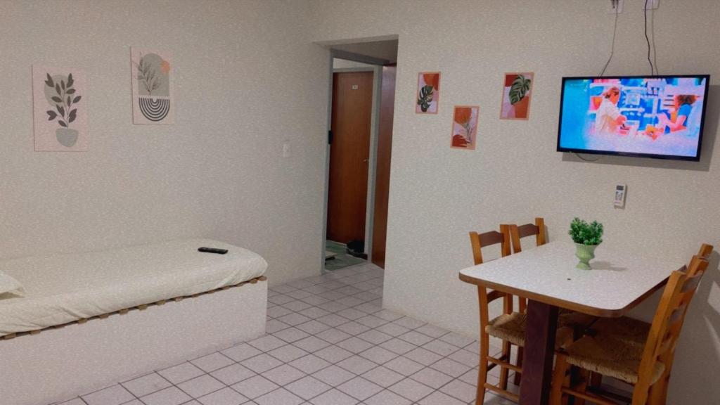 a room with a bed and a table and a tv at com churrasqueira em Canasvieiras in Florianópolis