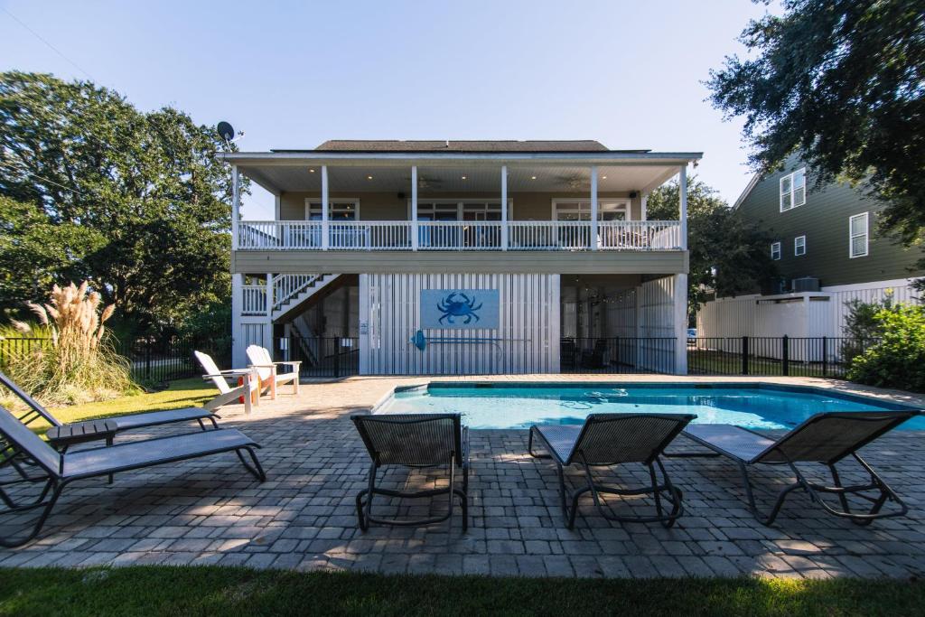 a swimming pool with chairs and a house at I'll Have Another in Edisto Island