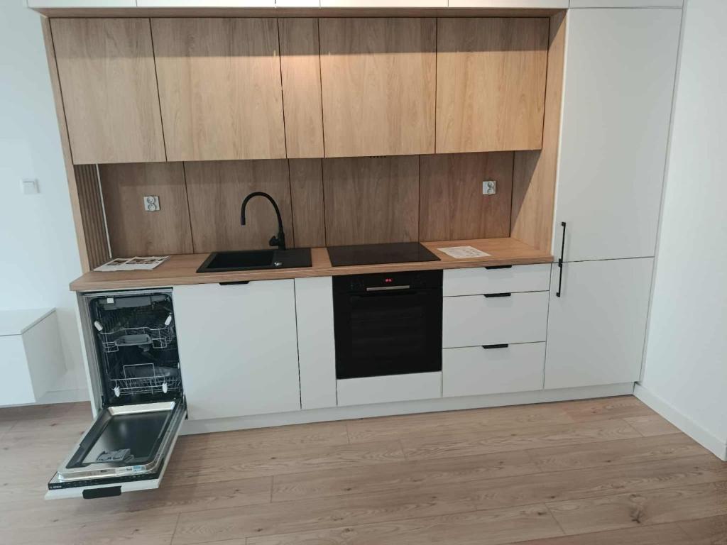 a kitchen with white cabinets and a black appliance at Old Town Apartment Elbląg in Elblag